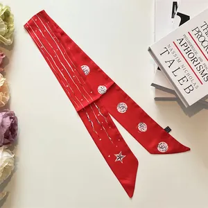 Détail d'un foulard en soie rouge étoilé posé sur des livres avec des fleurs blanches