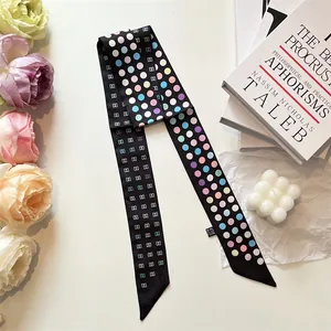 Elegant narrow black silk scarf with colorful polka dots on a white minimalist background