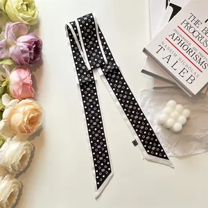 Elegant black and white polka dot silk twilly scarf styled with books and flowers