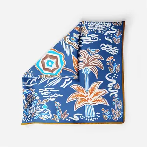 Close-up of a small square silk scarf with a navy tropical print and yellow rolled edges