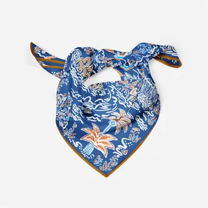 Detail of silk square scarf featuring navy tropical palm tree prints and rolled edges