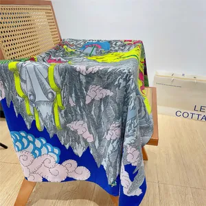 Detailed view of square silk scarf with mountain landscape print on rattan chair