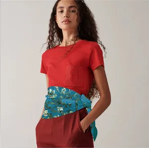 Detail of silk scarf with apricot blossom pattern paired with a red short-sleeve shirt