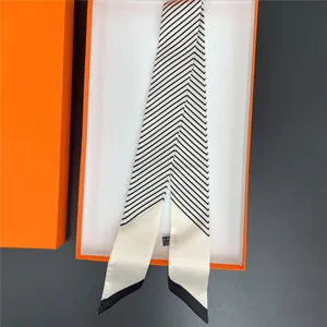 Sciarpa di seta minimalista a righe bianche e nere presentata in una confezione regalo arancione