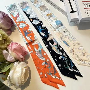 Silk-like long ribbon scarves with fantasy illustration prints in orange, black and cream