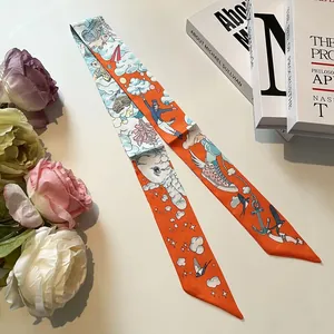 Macro detail of creamy white silk scarf with orange fantasy illustrations for bag handles