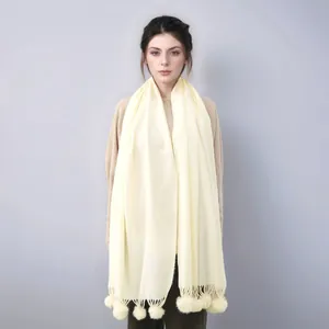 Détail d'un châle en cachemire beige avec pompons décoratifs pour un style hivernal chic