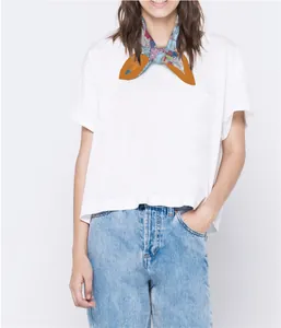 Detailansicht eines Seidenschals mit Blumenmuster und orangem Saum auf weißem Shirt