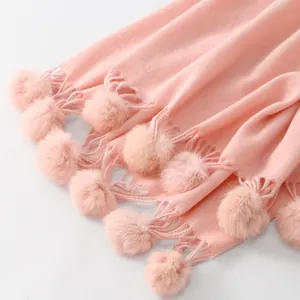 Gros plan d'une écharpe rose aspect cachemire avec texture douce, pompons et franges