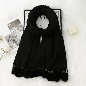 Détail d'une écharpe noire en imitation cachemire avec pompons doux et texture tricotée