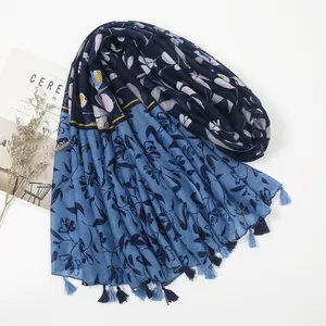 Detail of blue cotton-linen scarf with floral print and handmade tassels on the hem