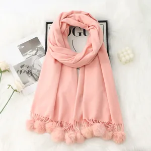 Détail d'une écharpe rose style cachemire avec pompons doux sur un tapis en fourrure