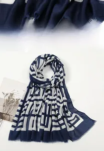 Detail eines blau-weißen Schals mit geometrischem Muster und feinen Fransenrändern