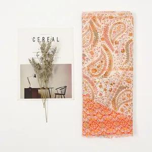 Detailed view of bohemian paisley print scarf with fringe edges and warm floral patterns