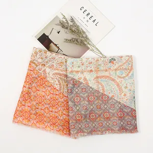 Detailed flat lay of bohemian paisley print scarf with frayed edges and warm orange tones