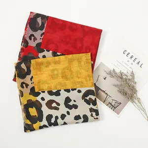 Detail of leopard print scarves in red and yellow linen with magazine and dried flowers
