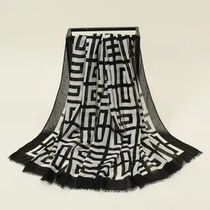 Detail eines klassisch schwarz-weißen Schals mit geometrischem Muster und Fransen am Rand