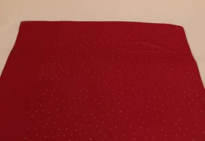 Detailaufnahme von rotem Chiffonschal mit glänzenden Gold-Strasssteinen und weichem Stoff