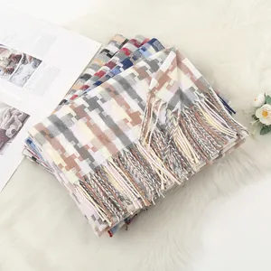 Detail of stacked winter scarves showing soft cashmere texture and fringe tassels