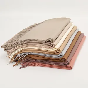 Stack of colorful cashmere-feel scarves with fringed edges showing thick warm texture