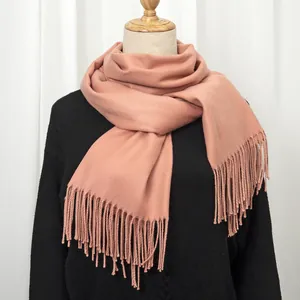 Pink cashmere feel winter scarf with long tassels on a model with a black sweater