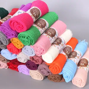 Detail of multi-color pleated cotton scarves with textured fringe and branded paper bands
