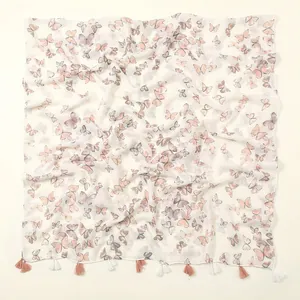 Dettaglio di stampa a farfalla su sciarpa in cotone beige con nappe rosa morbido