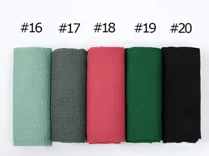 Detailed flat lay of pleated cotton scarves in mint green, dark grey, and pink tones