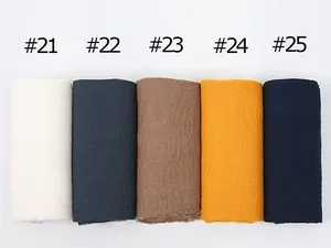 Detailed close-up of wrinkled cotton linen scarves in various solid colors with frayed edges