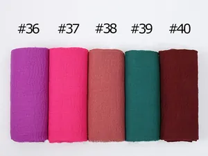 Close-up of pleated cotton linen scarves in purple, rose, brick red, dark green and red