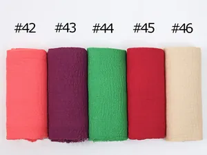 Detail view of cotton linen scarves in coral, purple, green, red, and beige textures