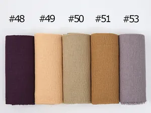 Detailed macro view of solid color crinkled cotton scarves in various Earth tone shades