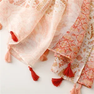 Détail d'une écharpe bohème avec motif paisley et pompons pour la plage