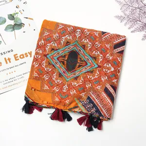 Détail d'une écharpe bohème aux motifs géométriques colorés et pompons décoratifs