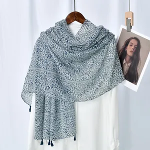 Blue and white paisley scarf with tassels hanging on a hanger for a stylish look