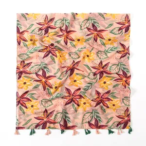 Detail of vintage floral cotton scarf showing pink fabric with red lily prints and tassels
