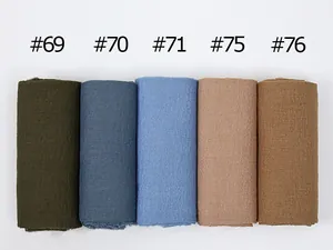 Macro view of textured crinkle scarves in diverse solid colors showing fabric details