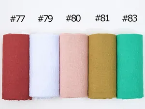 Detail view of cotton-linen scarves in five solid colors with crinkled texture and raw edges
