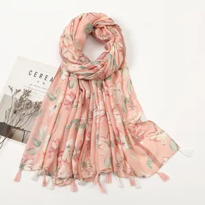 Flat lay of pink floral cotton linen shawl with delicate tassel fringe on white backdrop