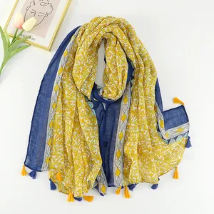 Close-up of ethnic floral print scarf with tassels on a white background with props