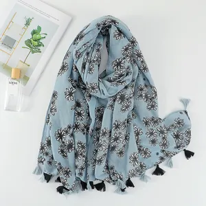 Detail of light blue floral cotton scarf with black and white daisy prints and fringe