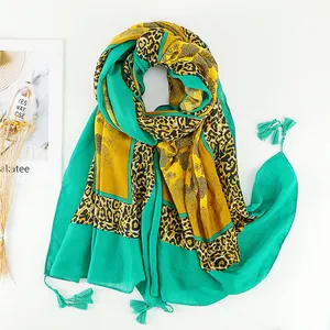 Detail of bohemian floral leopard print scarf with vibrant green tassels on white background
