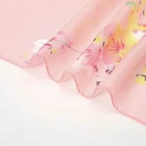 Détail macro d'un foulard en mousseline fleurie montrant le tissu rose délicat