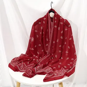 Détail d'une écharpe en mousseline rouge foncé avec des motifs cachemire blancs fins