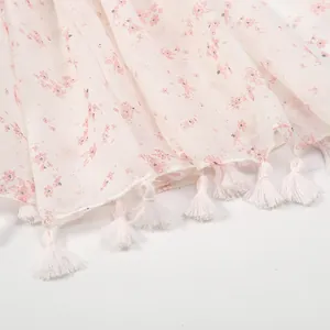 Detail of light pink floral scarf showing breathable fabric texture and fringe tassels