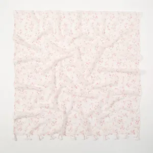 Detailed view of lightweight white scarf with pink floral print and cotton tassel fringes