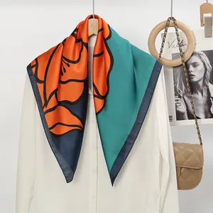 Detail of vibrant floral print silk square scarf with orange and teal color blocking