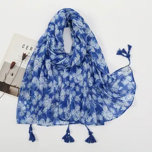 Detailed view of royal blue floral scarf with white daisy print and elegant fringe tassels