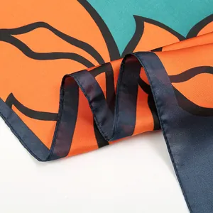 Detailed view of the silk scarf featuring orange floral prints and rolled edges