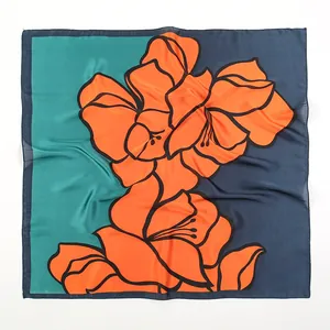 Detail of square silk scarf featuring vibrant orange lily prints on navy and green base